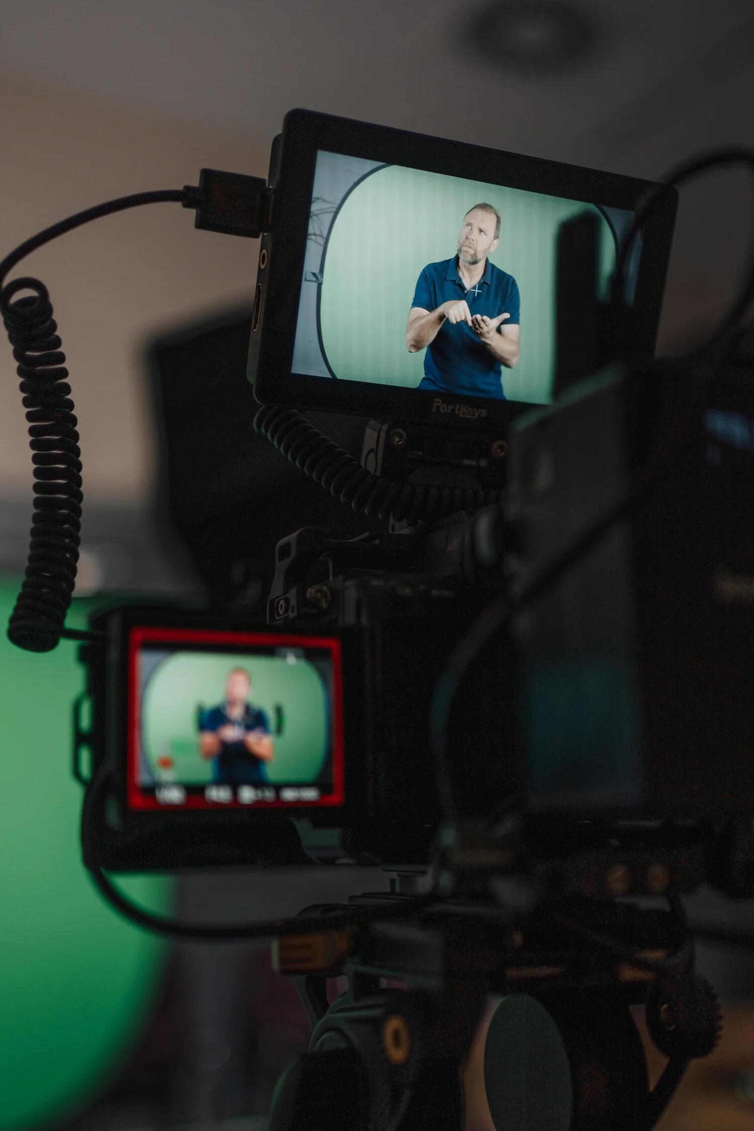 Videographer filming a Deaf presenter creating British Sign Language video content in a studio